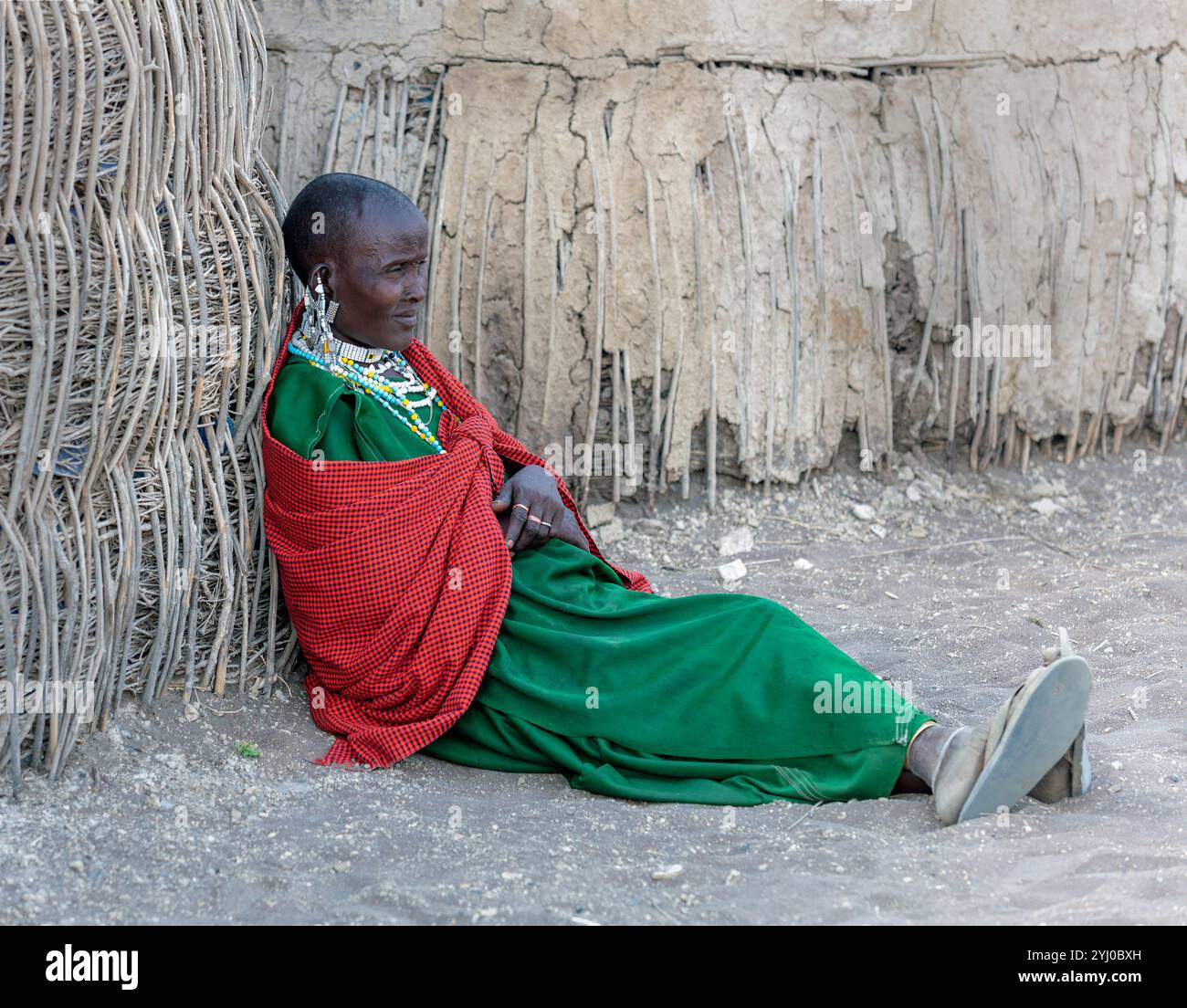 Femme Maasai âgée assise sur le sol en terre battue à l'extérieur de sa cabane Tanzanie, Afrique de l'est Banque D'Images