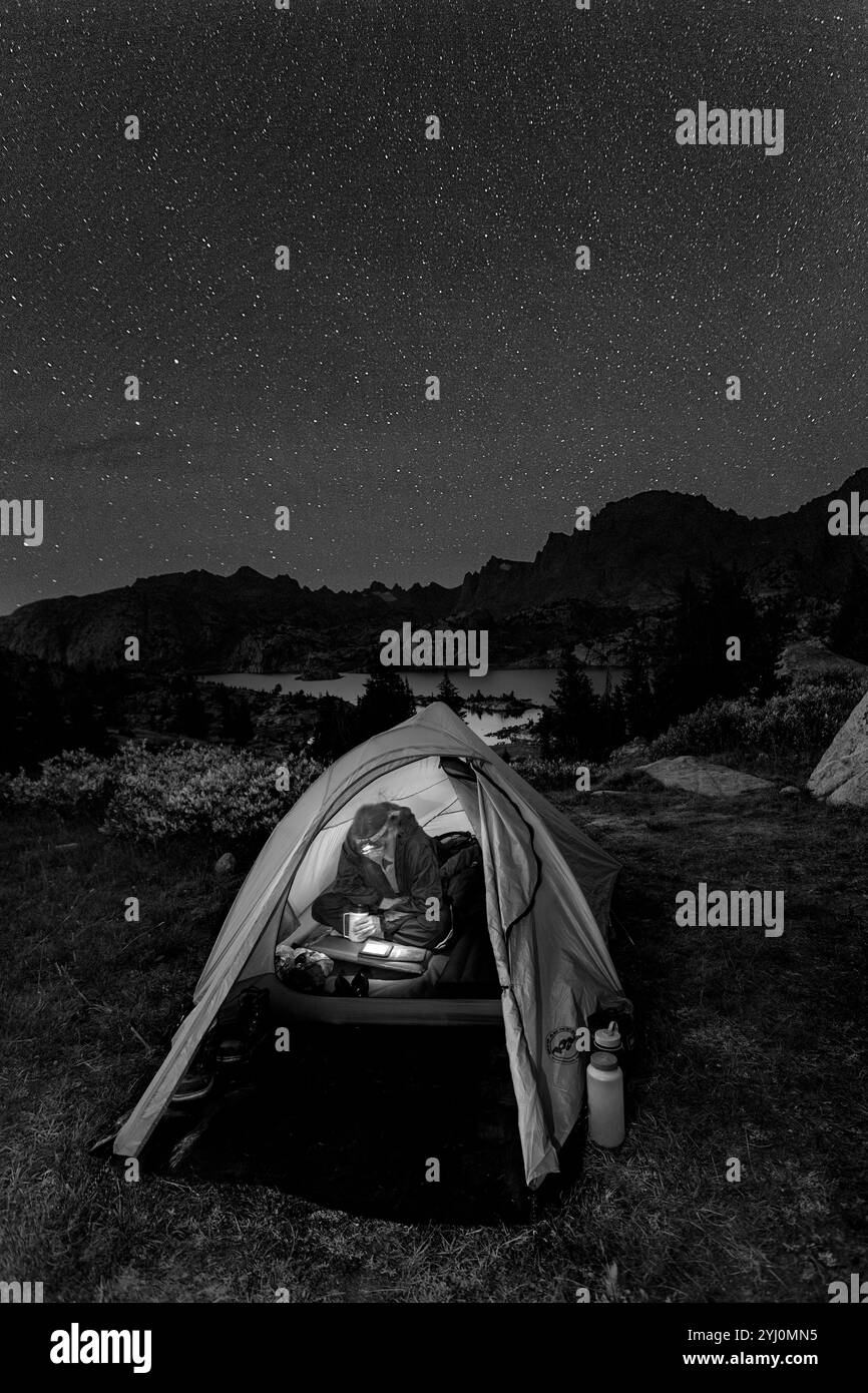 WY01750-00-BW...... WYOMING - détente et lecture d'un Kindle dans un camping au-dessus de Island Lake dans la chaîne de Wind River, Bridger Wilderness - Bridger Natio Banque D'Images