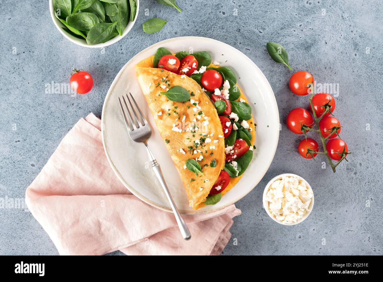 Omelette farcie aux tomates, fromage et épinards sur fond bleu. Vue de dessus. Banque D'Images