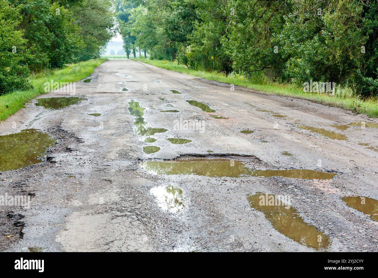 Nids de poule sur la route avec des pierres sur l'asphalte. La surface asphaltée est détruite sur la route. Mauvais état de la route, a besoin de réparation. Construction a Banque D'Images