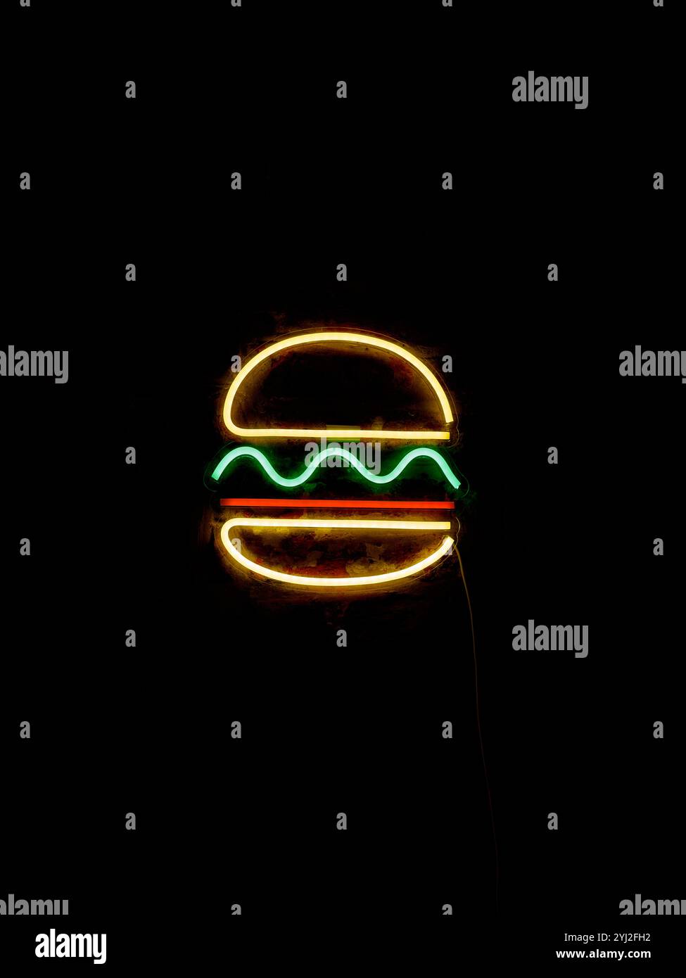 Signe néon d'un hamburger qui brille dans l'obscurité. Banque D'Images