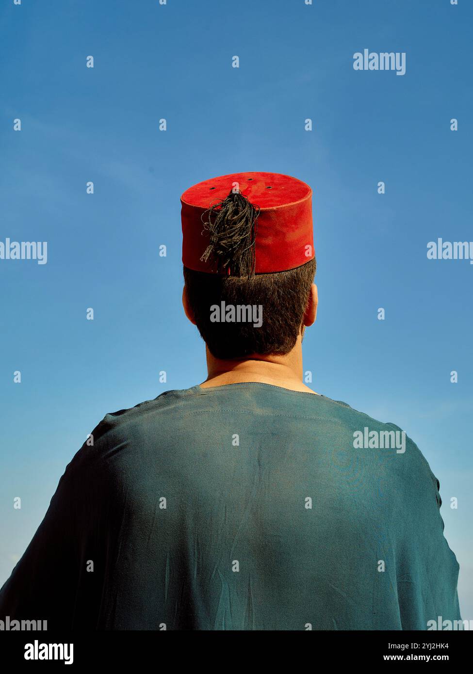 Un homme portant un chapeau traditionnel rouge regarde vers le ciel bleu clair, le Maroc Banque D'Images