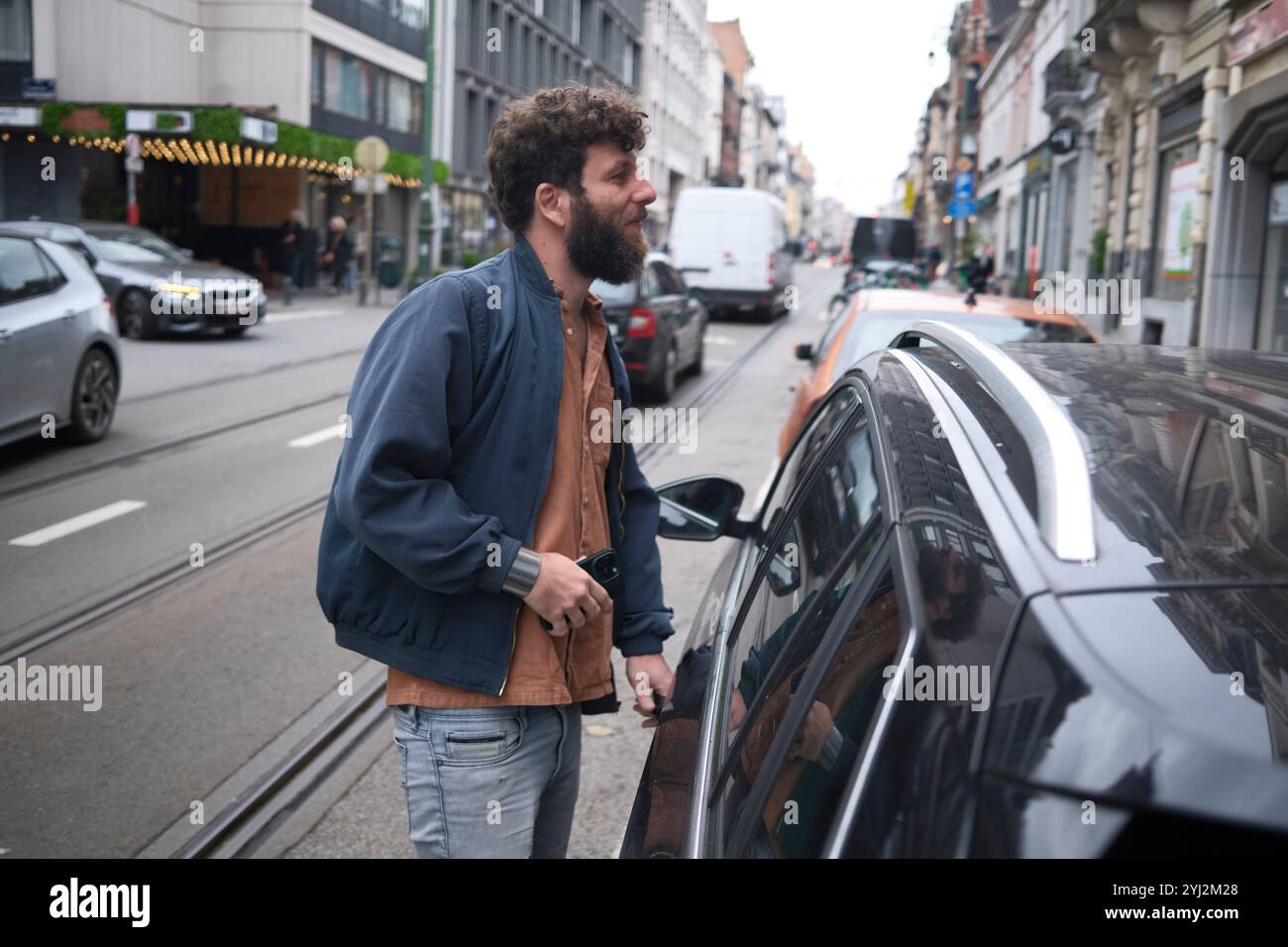 Homme souriant ouvrant une voiture dans une rue de la ville, Bruxelles, Belgique Banque D'Images