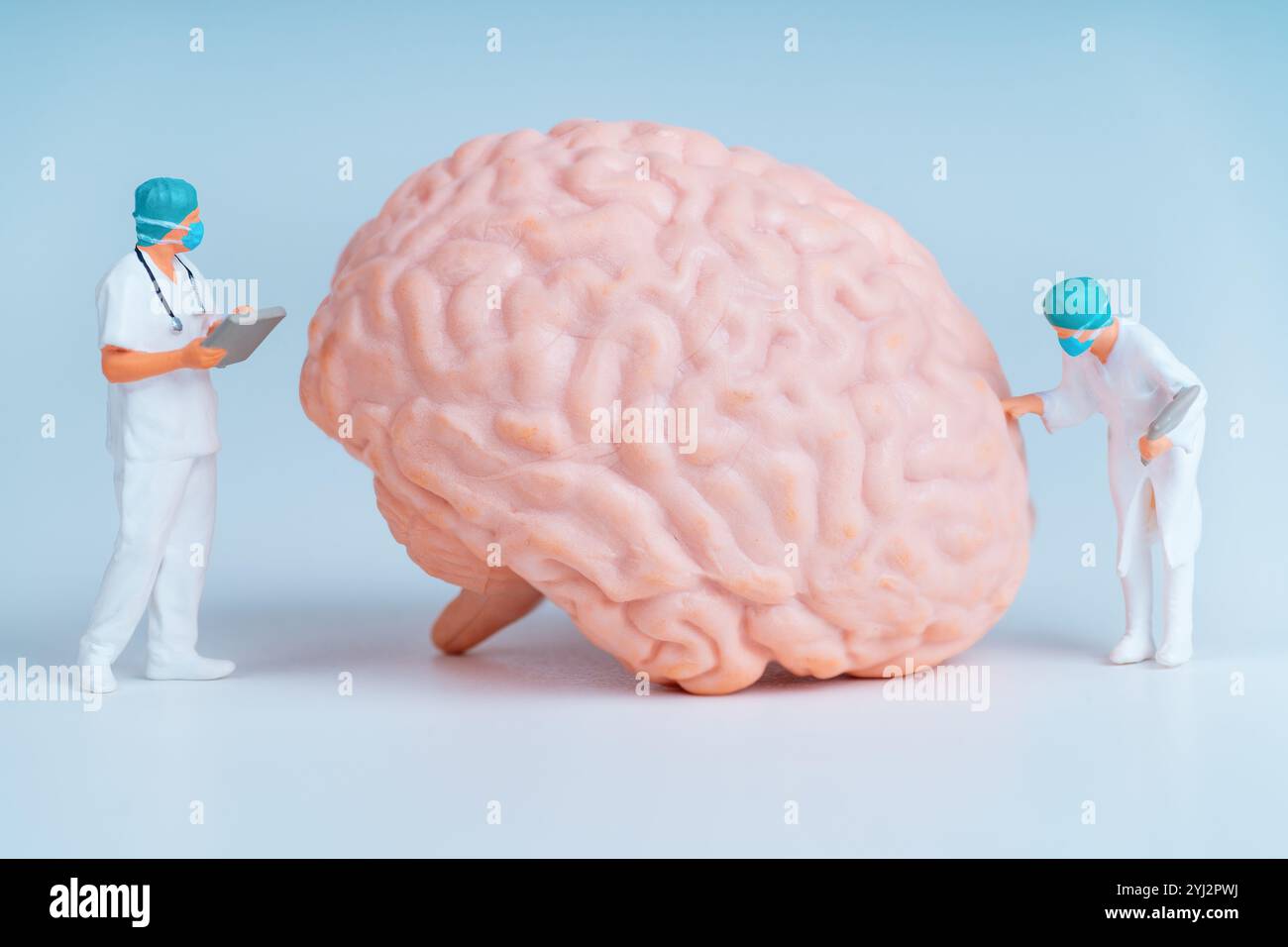 Deux médecins miniatures examinant un cerveau modèle dans un contexte médical. Banque D'Images