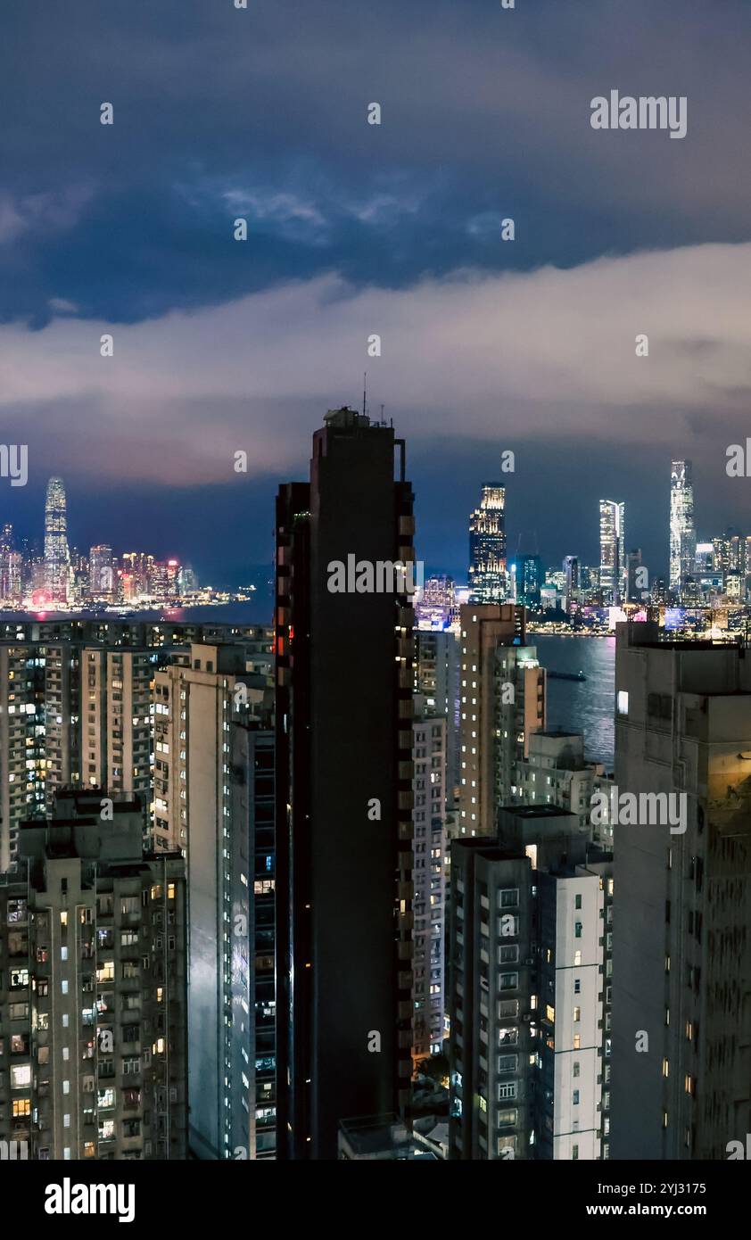 Des lumières brillantes ornent les gratte-ciel de Hong Kong, mettant en valeur un paysage urbain animé contre un ciel sombre. Banque D'Images