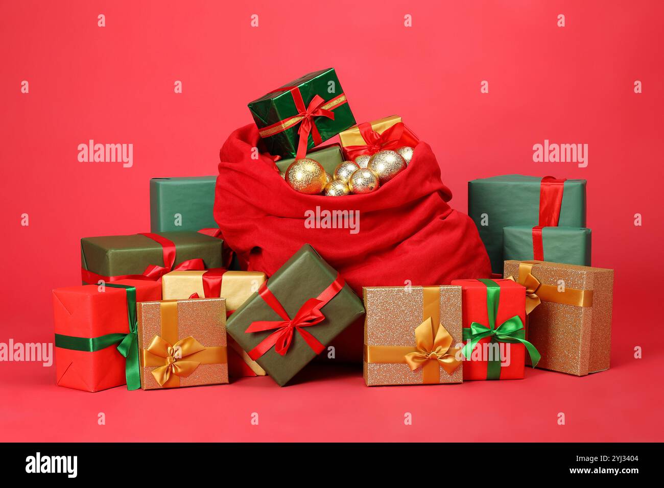 Sac de Père Noël avec des boules et des boîtes cadeaux sur fond rouge Banque D'Images