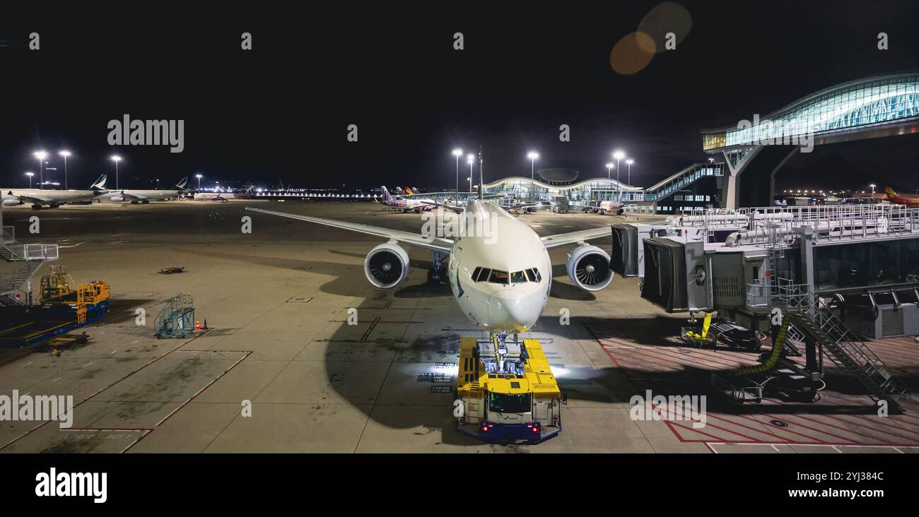 Un avion de passagers est en cours d'entretien et préparé pour son prochain vol à l'aéroport de Hong Kong sous les feux lumineux de l'aéroport. Banque D'Images