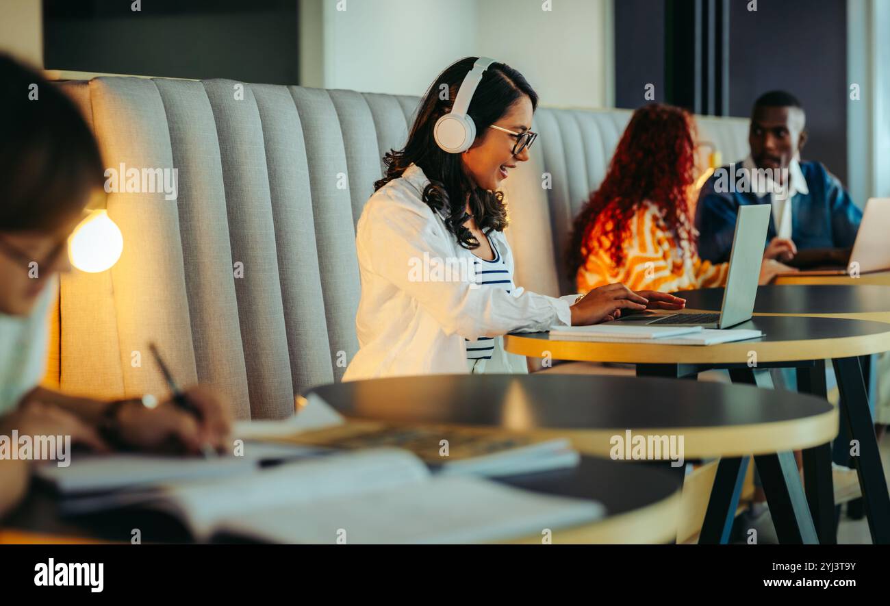 Étudiants joyeux engagés dans le coworking, le partage d'idées et l'étude dans un espace dynamique. La collaboration et la productivité sont évidentes lorsqu'ils fonctionnent avec lapt Banque D'Images