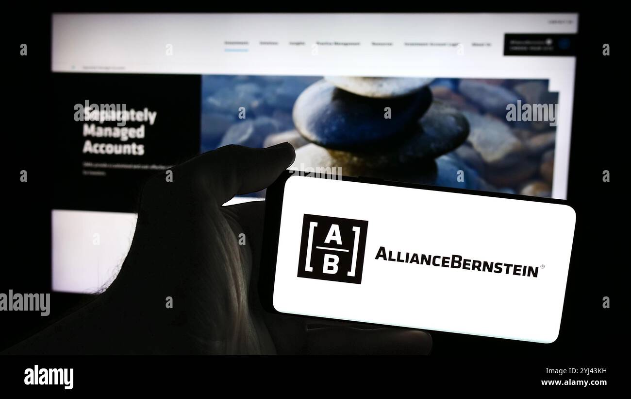 4 juillet 2024, Allemagne : dans cette illustration photo, un homme tient un téléphone portable avec le logo de la société d'investissement américaine AllianceBernstein Holding LP (AB) devant la page web. (Crédit image : © timon Schneider/SOPA images via ZUMA Press Wire) USAGE ÉDITORIAL SEULEMENT ! Non destiné à UN USAGE commercial ! Banque D'Images