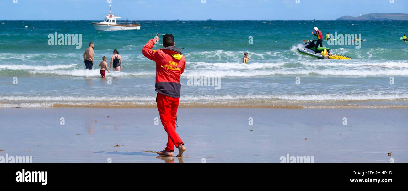 Une image panoramique des sauveteurs de la RNLI Royal National Lifeboat institution travaillant ensemble à Towan Beach à Newquay en Cornouailles au Royaume-Uni. Banque D'Images