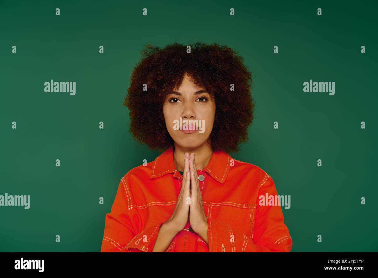 Une jeune femme afro-américaine aux cheveux bouclés transmet de forts sentiments tout en se tenant devant un fond vert. Banque D'Images