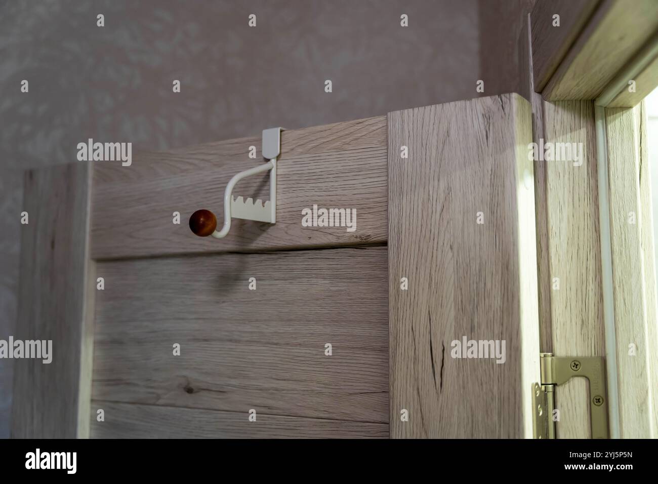 Gros plan d'un crochet de porte en métal moderne dans une salle de bain, utilisé pour accrocher une serviette et un vêtement. Le crochet est conçu pour u facile et pratique Banque D'Images