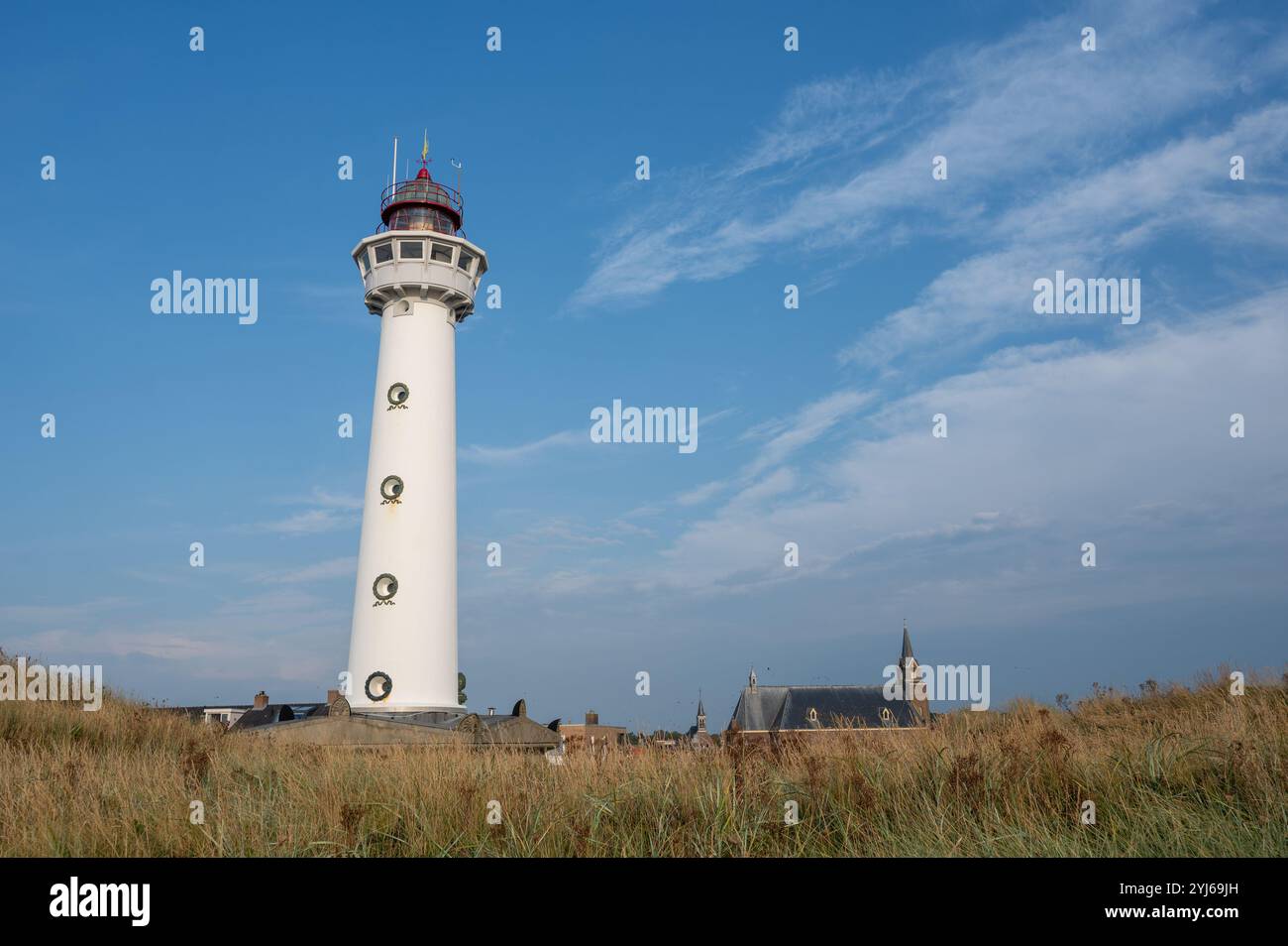 Le phare blanc d'environ 28 m de haut J.C.J. van Speijk à Egmond aan Zee, Hollande du Nord, pays-Bas avec l'église catholique Agnes, herbe de plage Banque D'Images