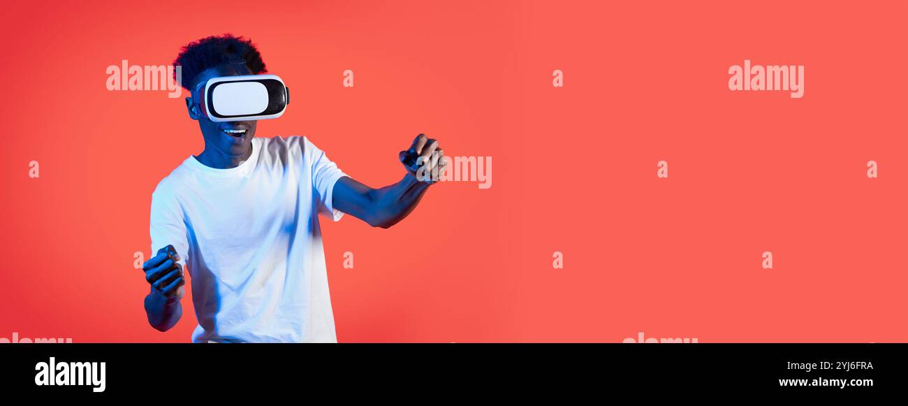 Un jeune homme est entièrement immergé dans une expérience de réalité virtuelle, portant un casque et souriant tout en interagissant avec des éléments numériques. Le dos vibrant Banque D'Images