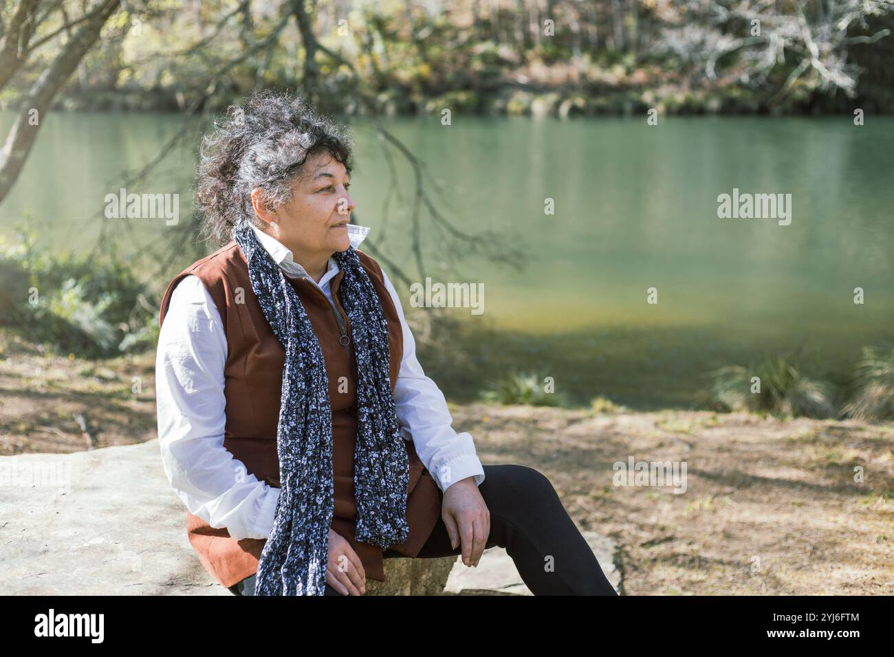 Une femme cubaine profite d'un moment paisible assis au bord de la rivière tranquille à Fragas do Eume, Galice, Espagne Banque D'Images