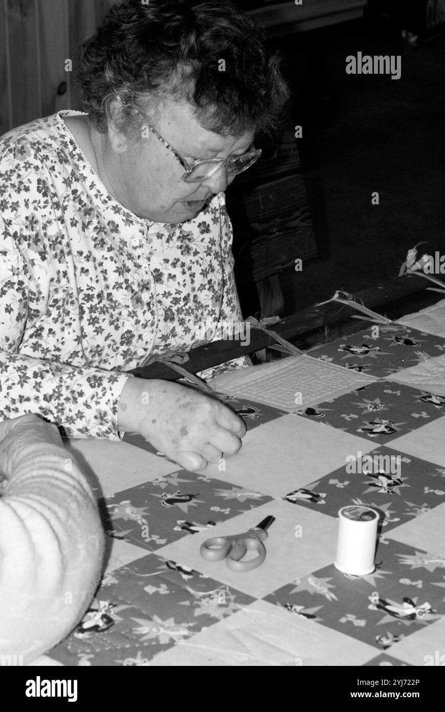 Femme caucasienne âgée de 60 à 70 ans cousant une courtepointe au WNC Farmers Market, Asheville, Caroline du Nord, États-Unis. Banque D'Images