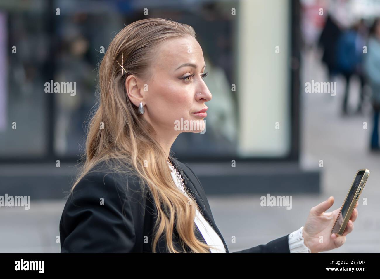 Portrait d'une femme sophistiquée d'apparence européenne, 35-40 ans, avec un flou d'une ville moderne en arrière-plan. Banque D'Images