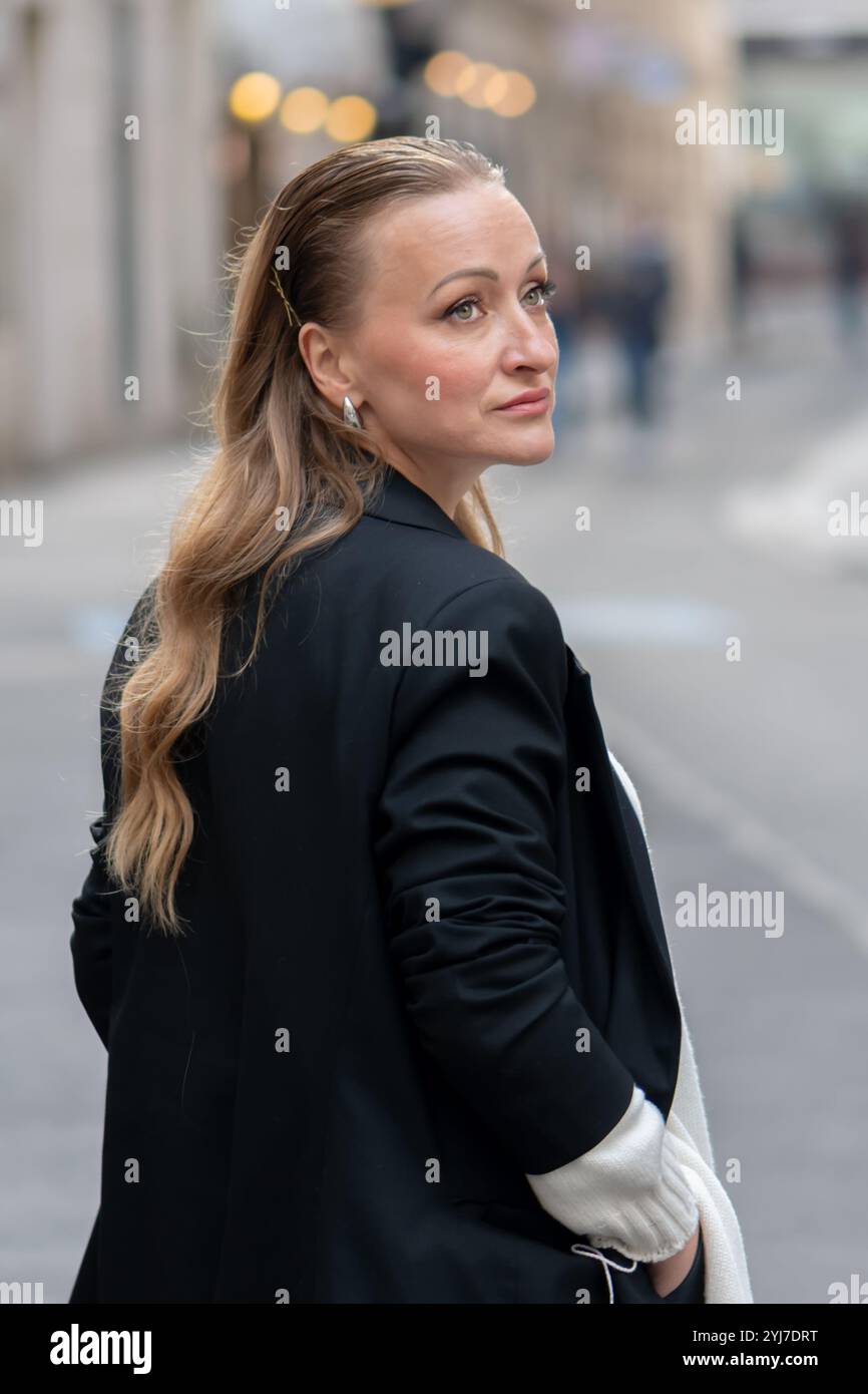 Portrait d'une femme sophistiquée d'apparence européenne, 35-40 ans, avec un flou d'une ville moderne en arrière-plan. Banque D'Images