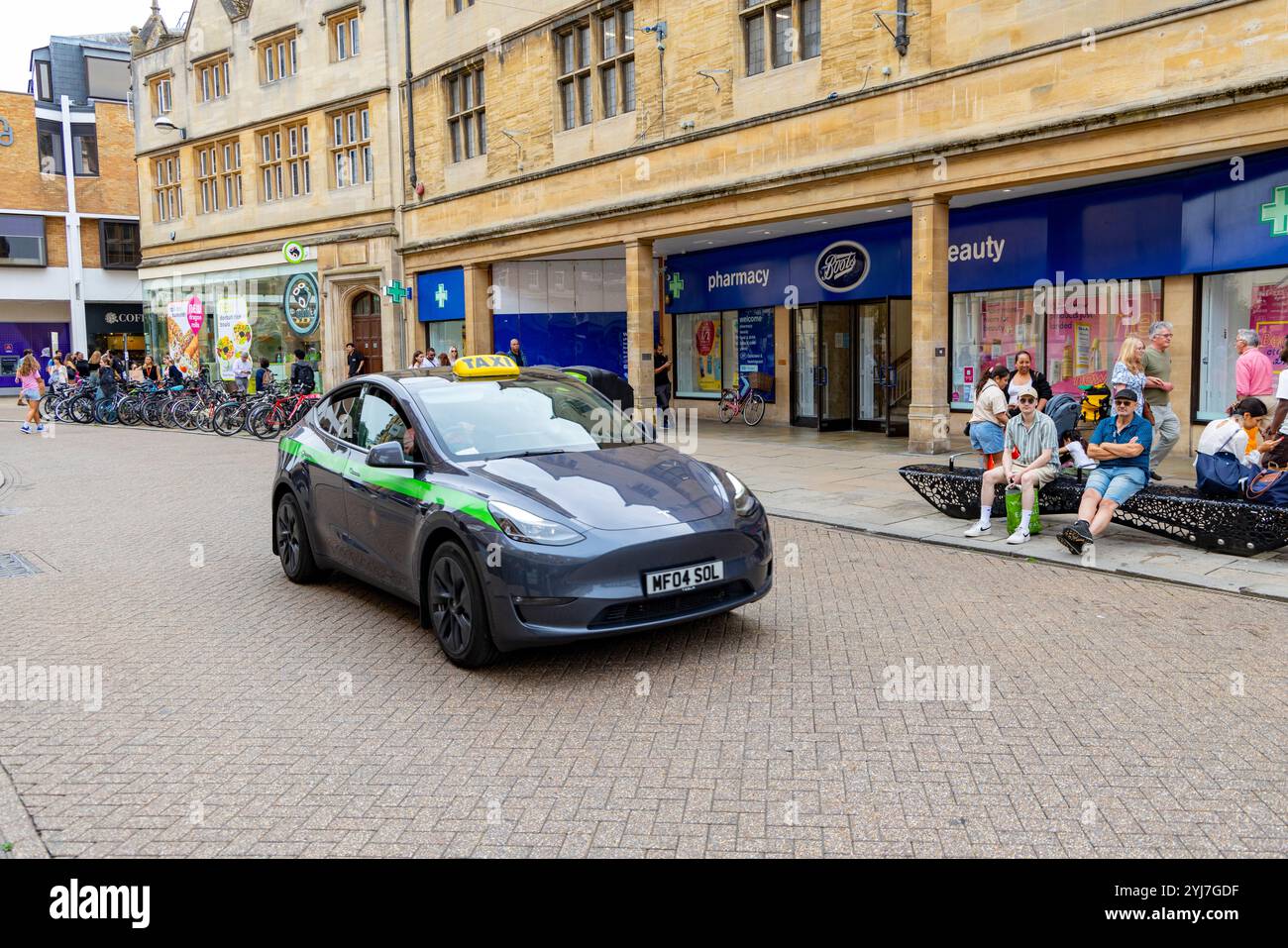 Tesla modèle y véhicule électrique travaillant comme un taxi public conduisant à travers le centre-ville de Cambridge, Angleterre, Royaume-Uni, 2024 Banque D'Images