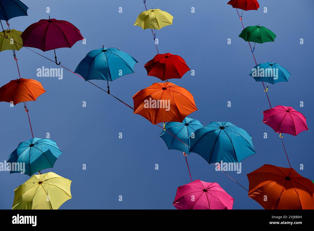 Parapluies colorés lumineux vibrants sur un fond de ciel bleu. Banque D'Images