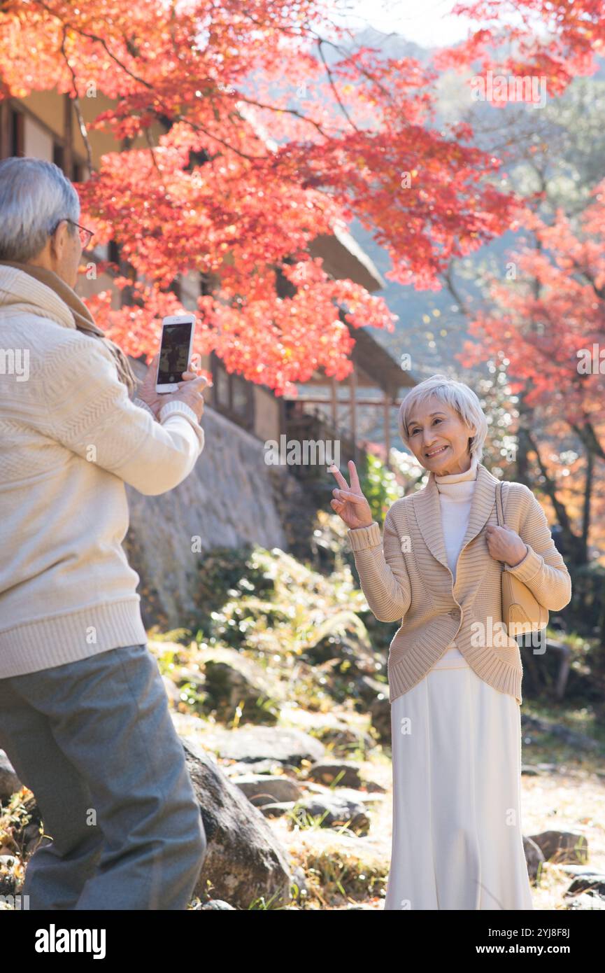 Couple senior photographié avec un appareil photo sur fond de feuille d'automne Banque D'Images