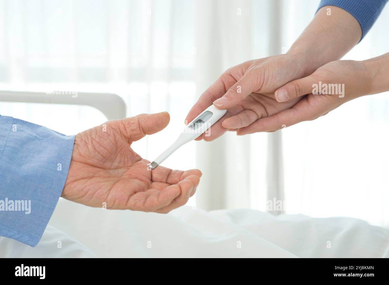 L'infirmière remet le thermomètre au patient dans le lit d'hôpital Banque D'Images