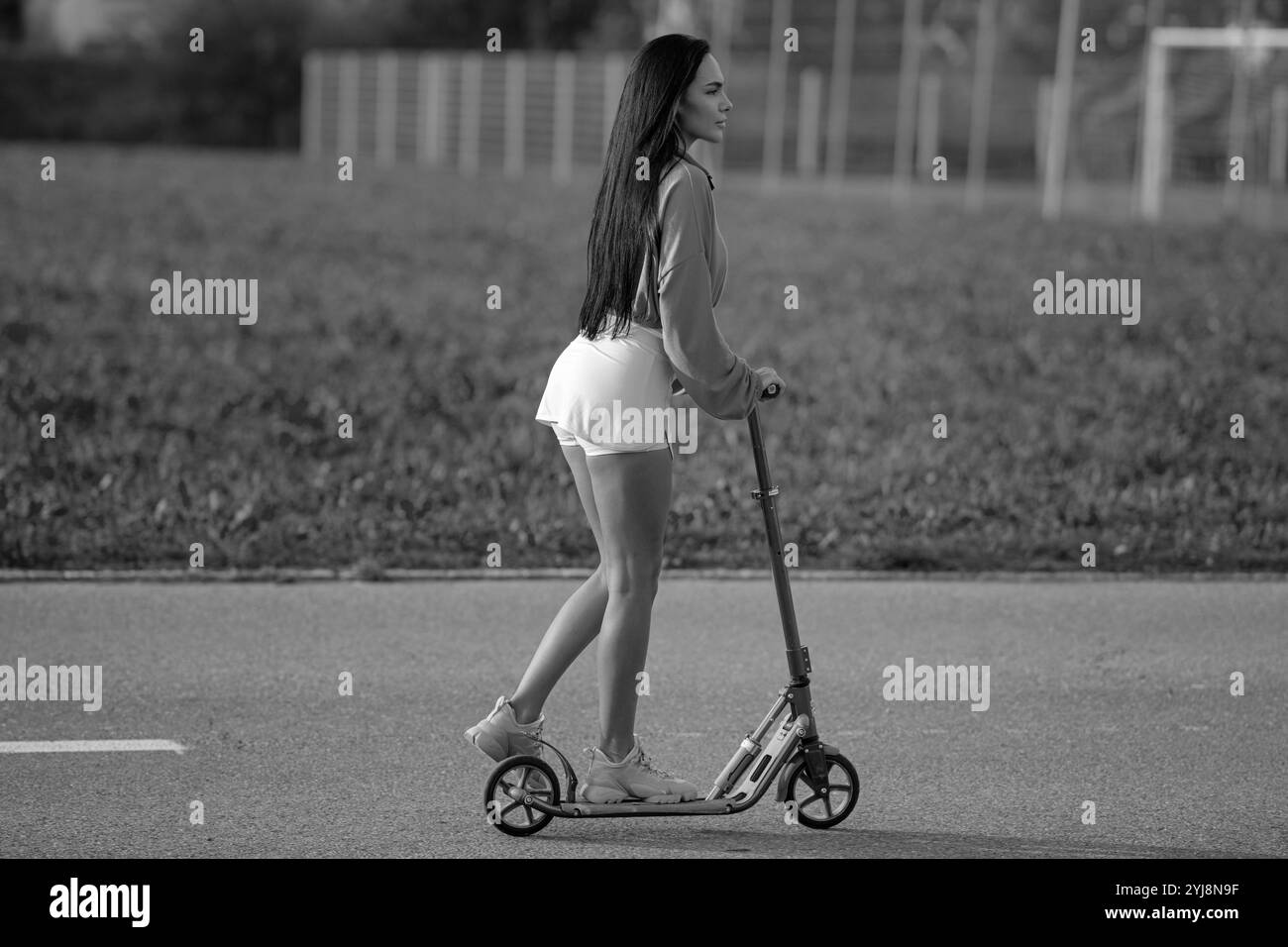 Mode de vie des filles. Cool jeune femme debout sur scooter drôle. Scooter pour fille. Une fille monte un scooter en short. Sports d'été et plein air actif Banque D'Images