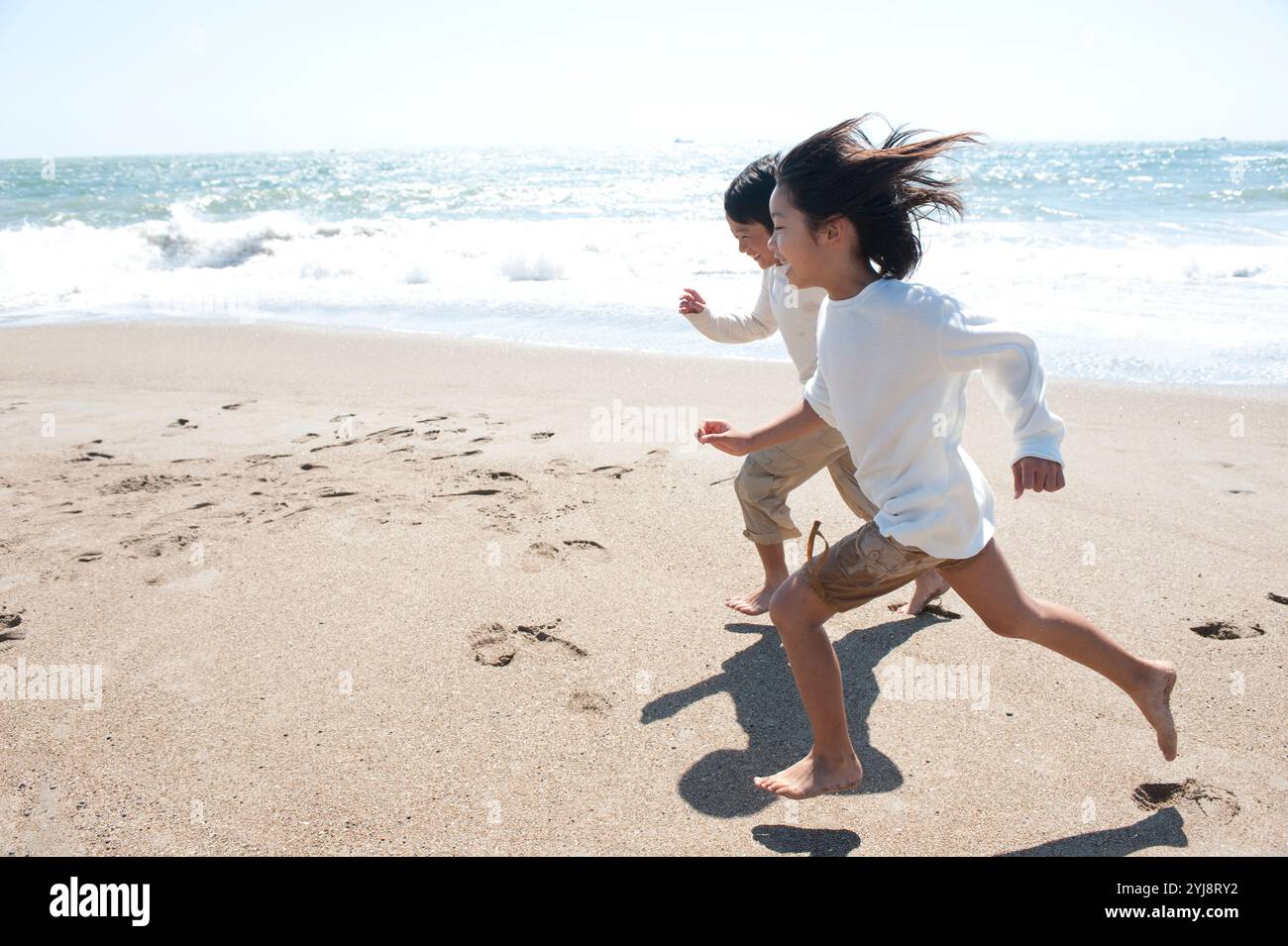 Enfants homme et femme courant le long de la mer Banque D'Images