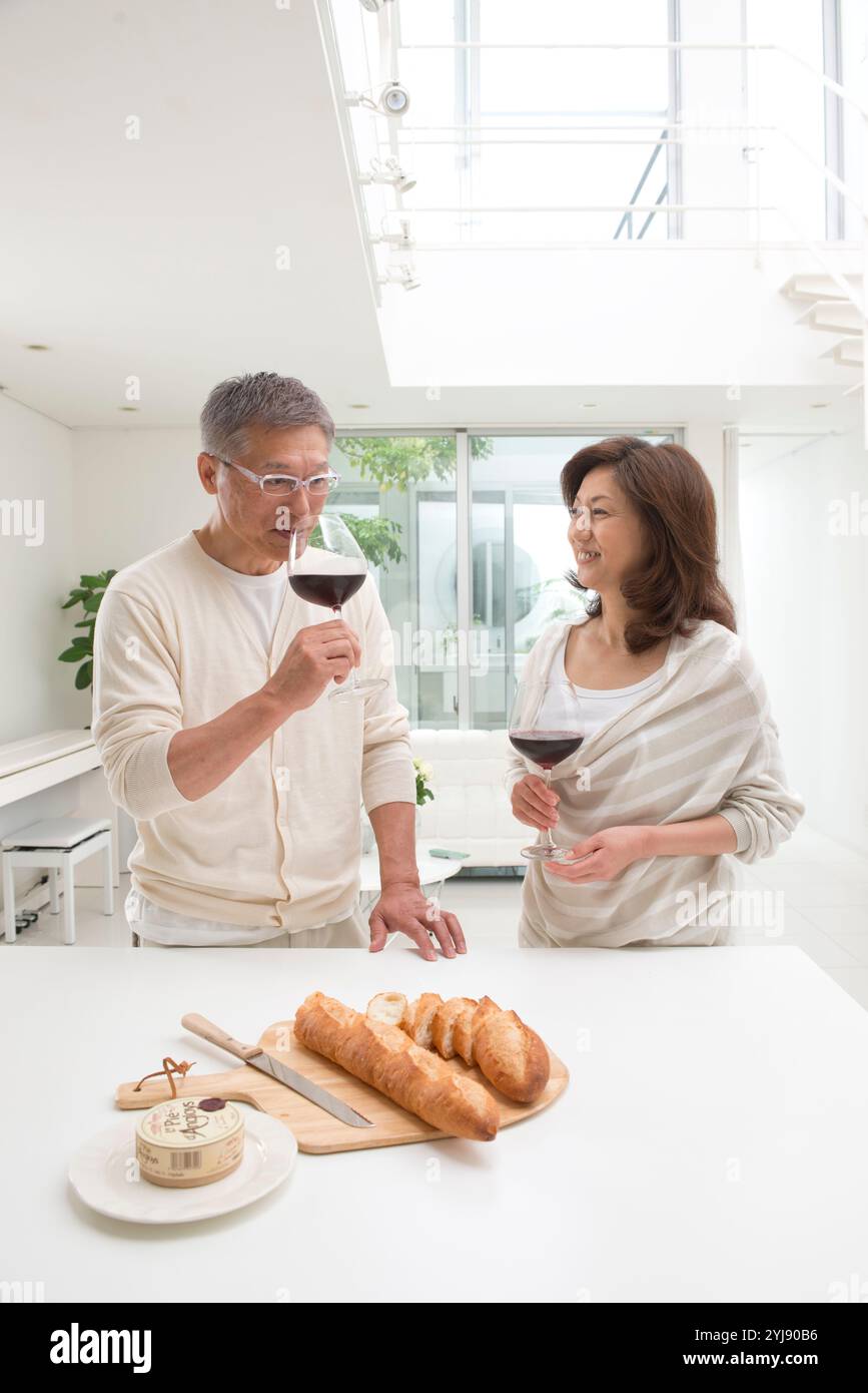 Couple d'âge moyen buvant du vin rouge dans la salle à manger Banque D'Images