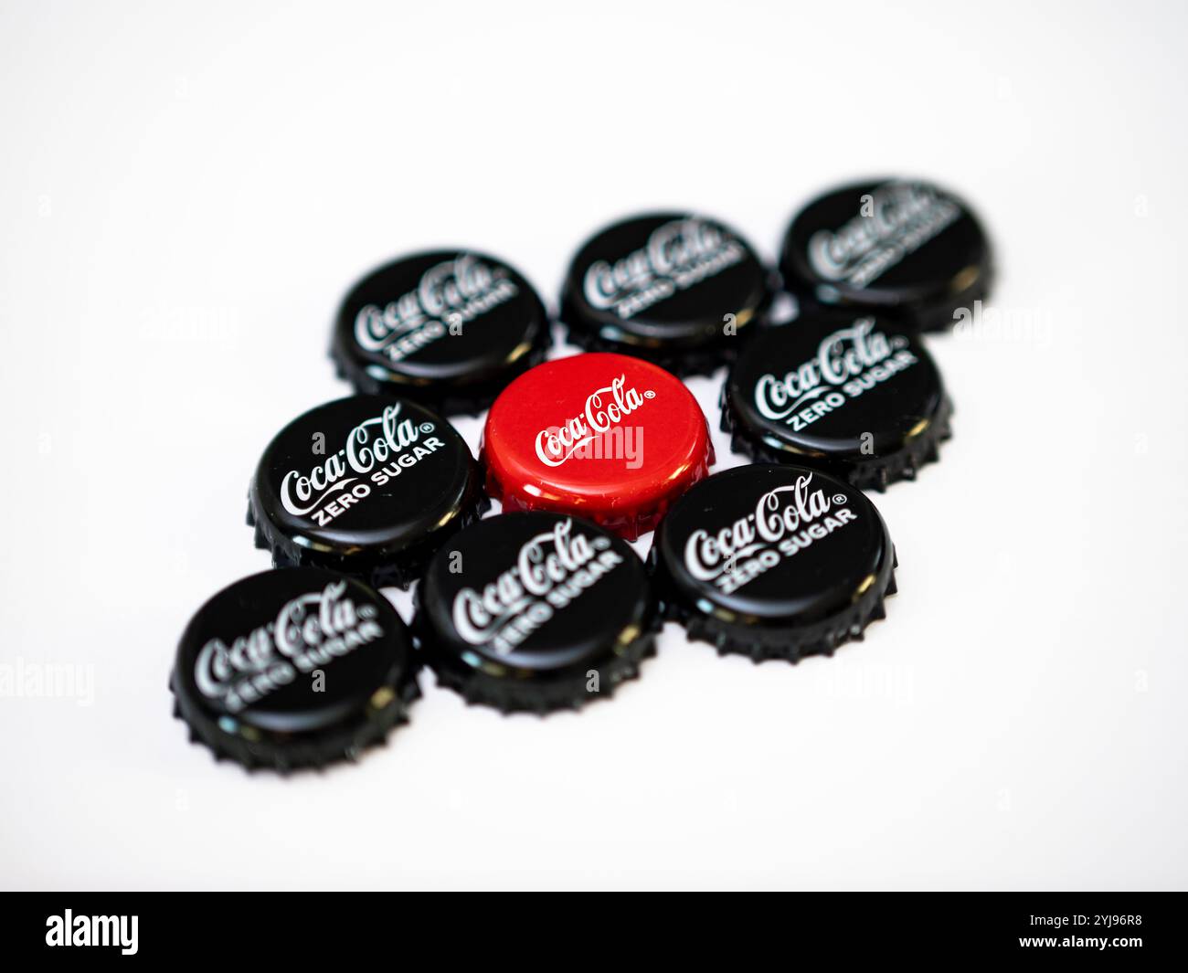 Bouchons de bouteille Coca Cola sur un fond blanc. Différents produits de coke comme le goût original et zéro sucre. Le chapeau rouge se trouve au centre. Banque D'Images