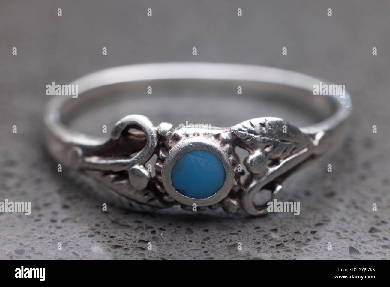 Gros plan de la bague amérindienne turquoise argentée sur le comptoir en granit. Petite pierre bleue. Banque D'Images