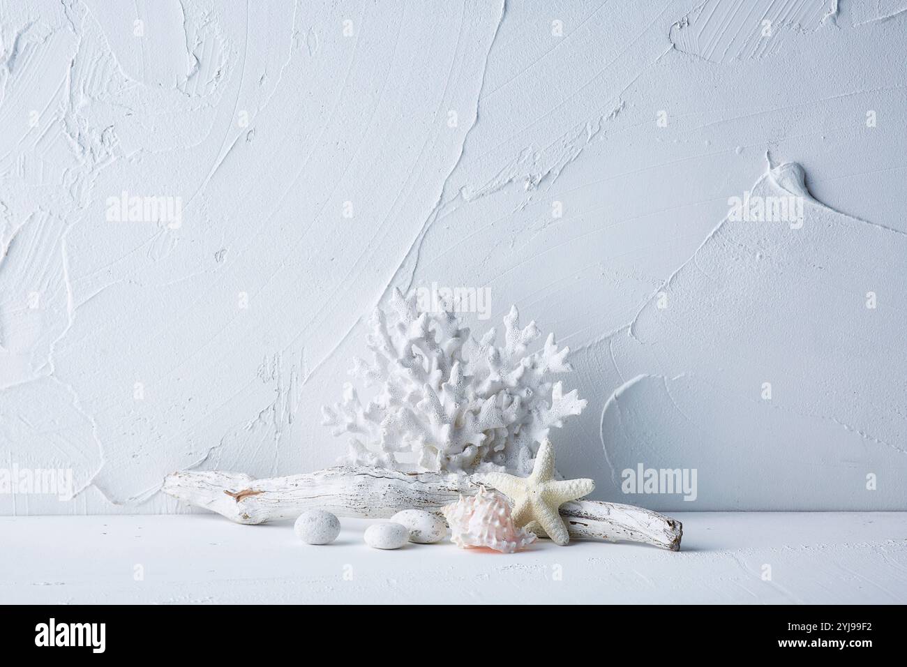 Corail, bois flotté, coquillages, étoiles de mer et galets sur table blanche Banque D'Images