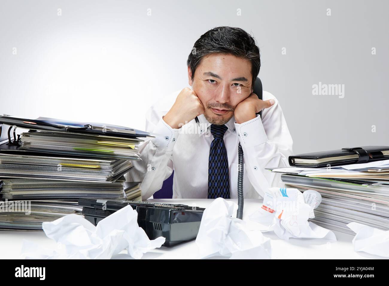 Employé de bureau au téléphone à son bureau avec une pile de travail Banque D'Images