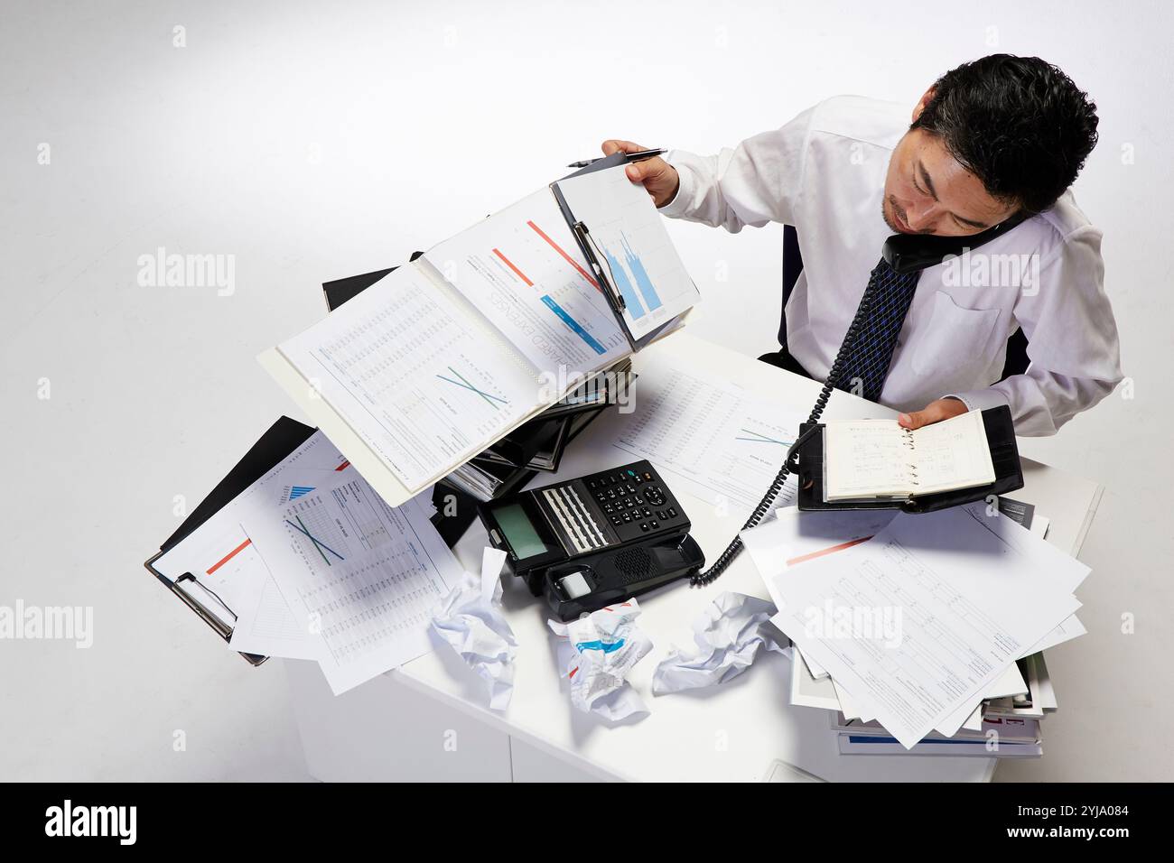 Employé de bureau au téléphone à son bureau avec une pile de travail Banque D'Images