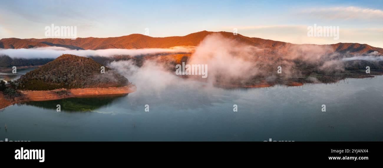Vue panoramique aérienne du lever du soleil sur un lac de montagne brumeux à Howqua Inlet sur le lac eildon à Victoria, Australie. Banque D'Images
