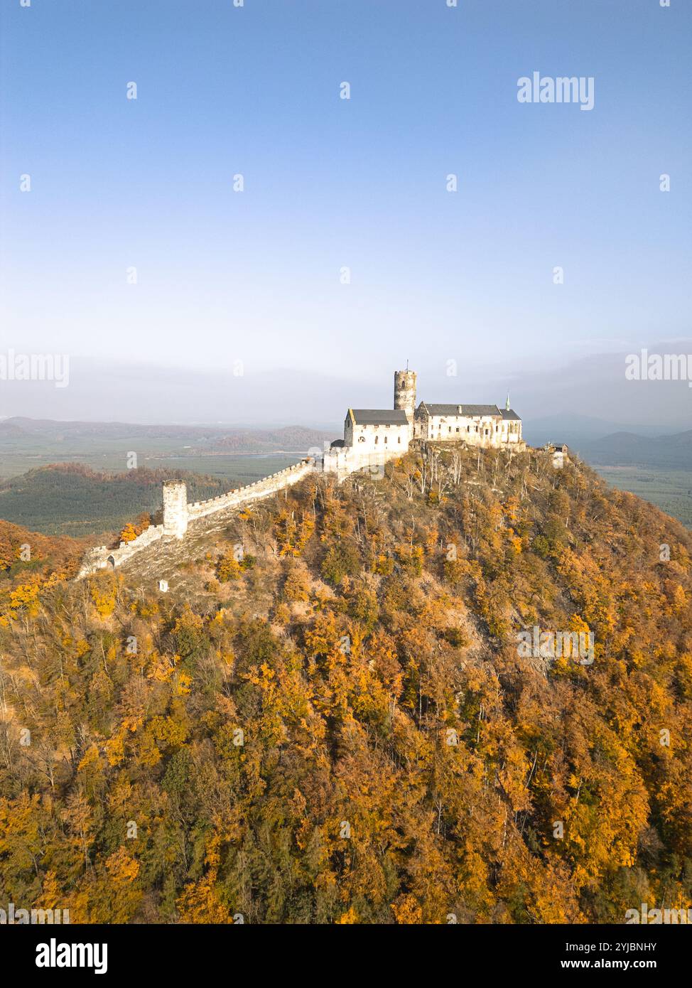 Le château médiéval de Bezdez se dresse majestueusement au sommet d'une colline, entouré de couleurs d'automne vibrantes. Le ciel dégagé et le feuillage riche créent une toile de fond pittoresque, mettant en valeur la beauté de la saison. Banque D'Images