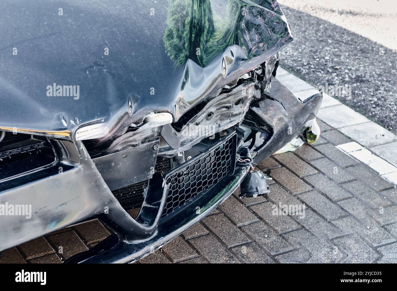 Voiture noire avec de graves dommages à l'avant après une collision. La photo met en évidence l'impact important et les dommages causés au véhicule, ce qui en fait un puissant Banque D'Images