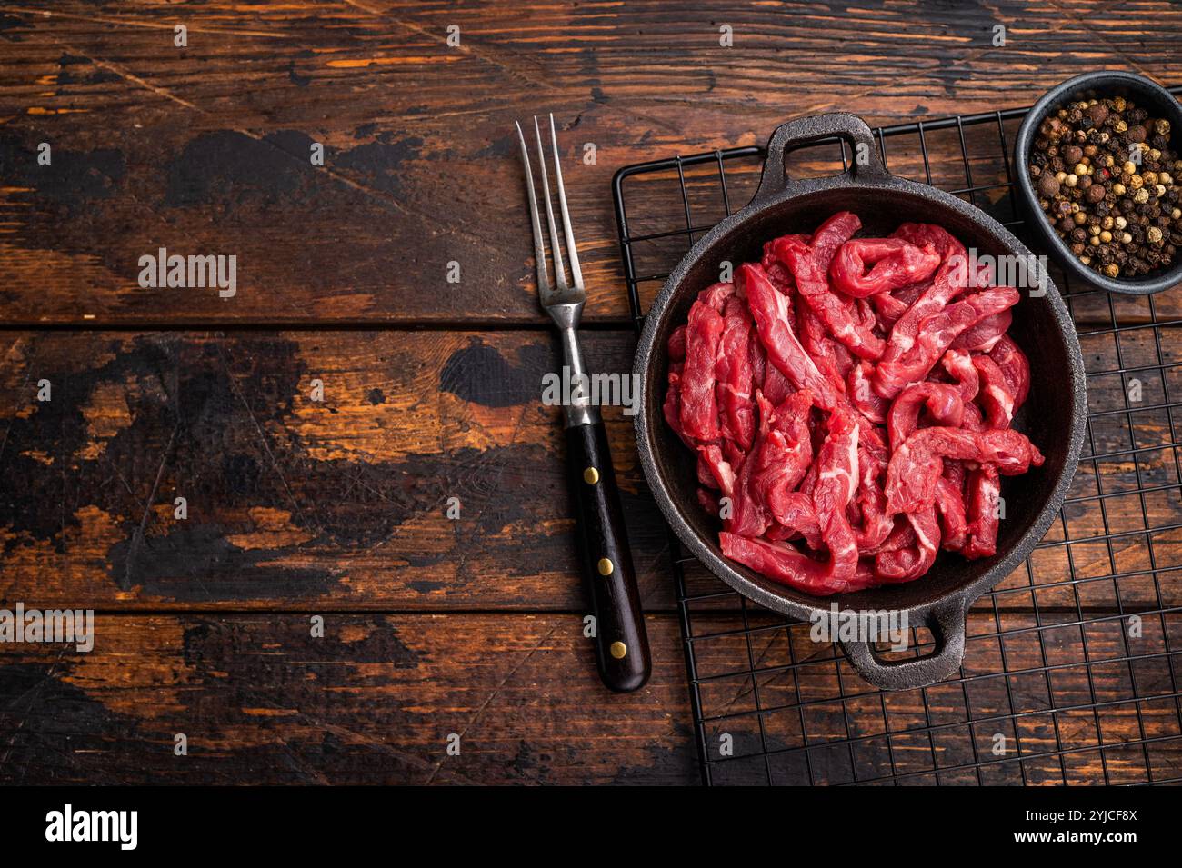 Tranches de viande de boeuf crue pour stroganoff de boeuf dans une poêle. fond en bois. vue de dessus Banque D'Images