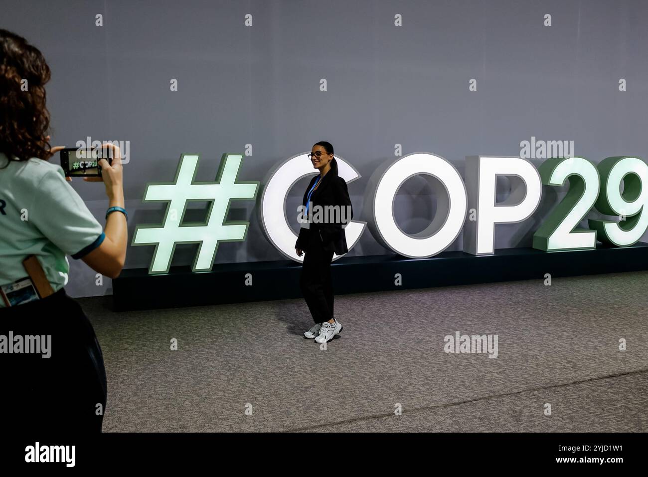 Bakou, Azerbaïdjan, 14 novembre 2024. Les participants marchent devant un logo de la COP29 pendant la COP29 de la Conférence des Nations Unies sur les changements climatiques, un événement organisé par la CCNUCC au stade olympique de Bakou. La COP29, qui se déroulera à partir de novembre 11-22, se concentre sur les marchés du carbone et le financement de la durabilité et de l’atténuation. Crédit : Dominika Zarzycka/Alamy Live News. Banque D'Images