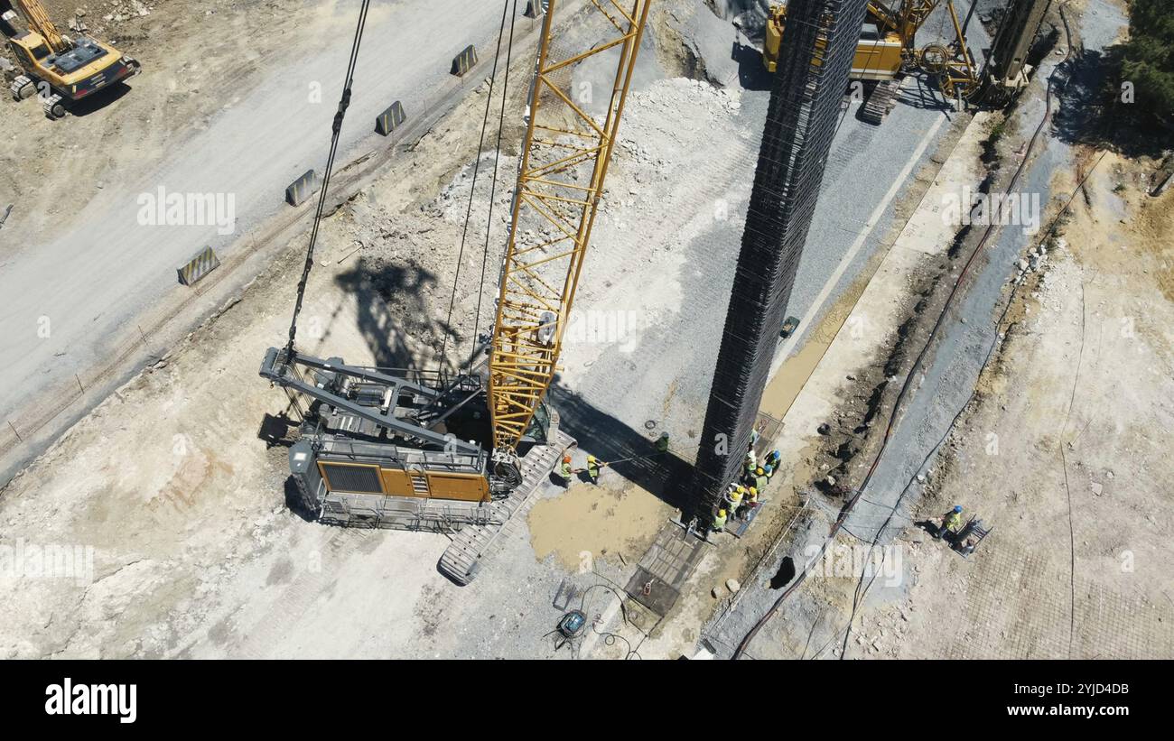 Grue levage barre d'armature avec ouvriers sur un chantier de construction vu d'en haut Banque D'Images