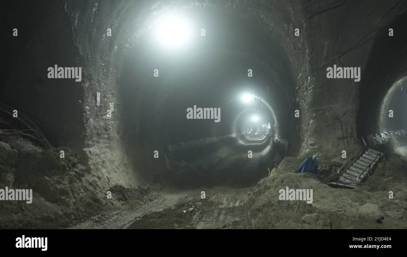 Tunnel souterrain éclairé en construction avec des machines lourdes et des lumières vives Banque D'Images