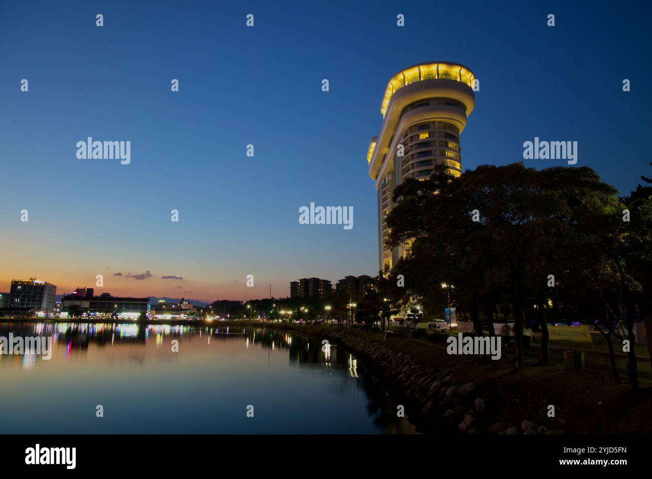 Gangneung, Corée du Sud - 3 novembre 2024 : une vue imprenable sur l'hôtel Skybay qui se reflète sur le lac Gyeongpodae au coucher du soleil. Les lumières de l’hôtel brillent Banque D'Images