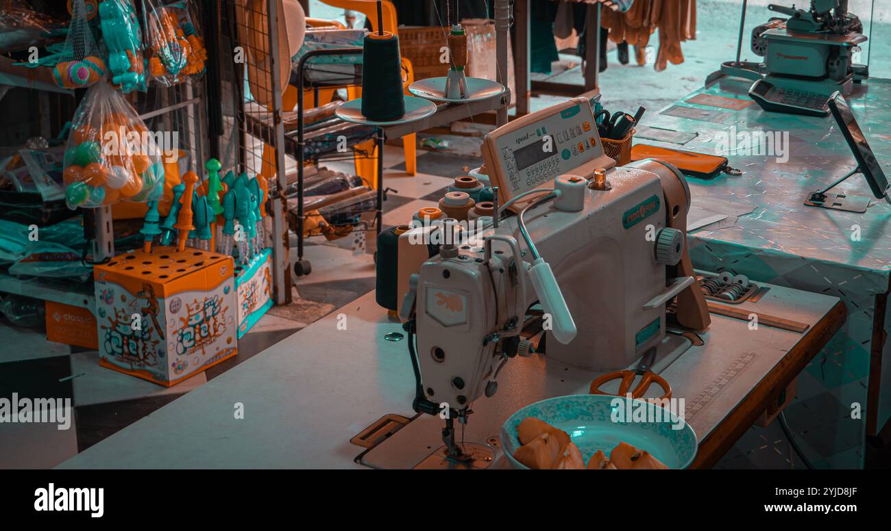 Espace de travail de couture rempli de bobines de fil vibrantes, de machines à coudre et de divers matériaux d'artisanat, offrant un aperçu de l'animation et de la créativité Banque D'Images