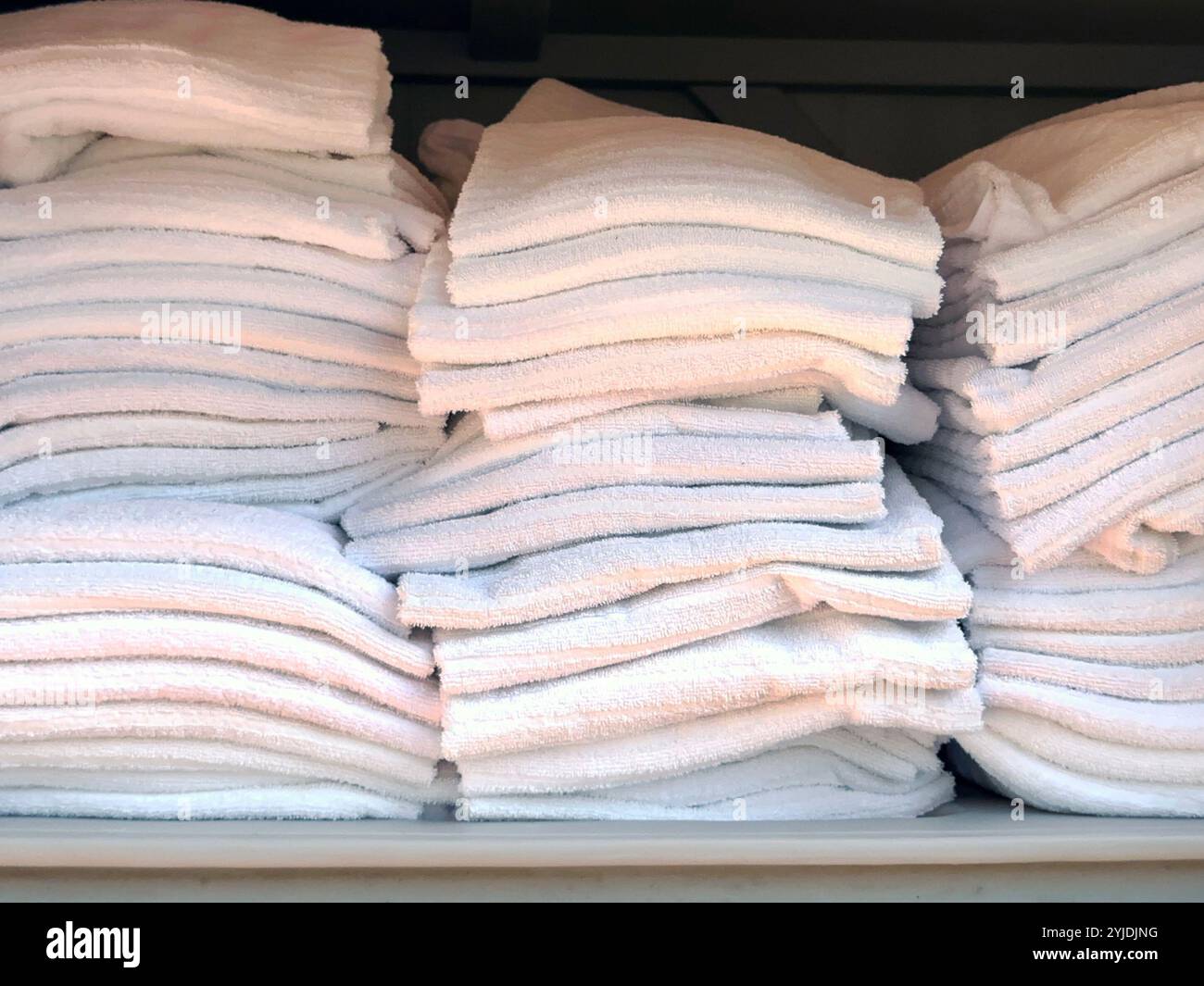 Piles de serviettes blanches moelleuses dans une armoire de rangement à la piscine extérieure d'un hôtel - Image de stock capturée avec un smartphone