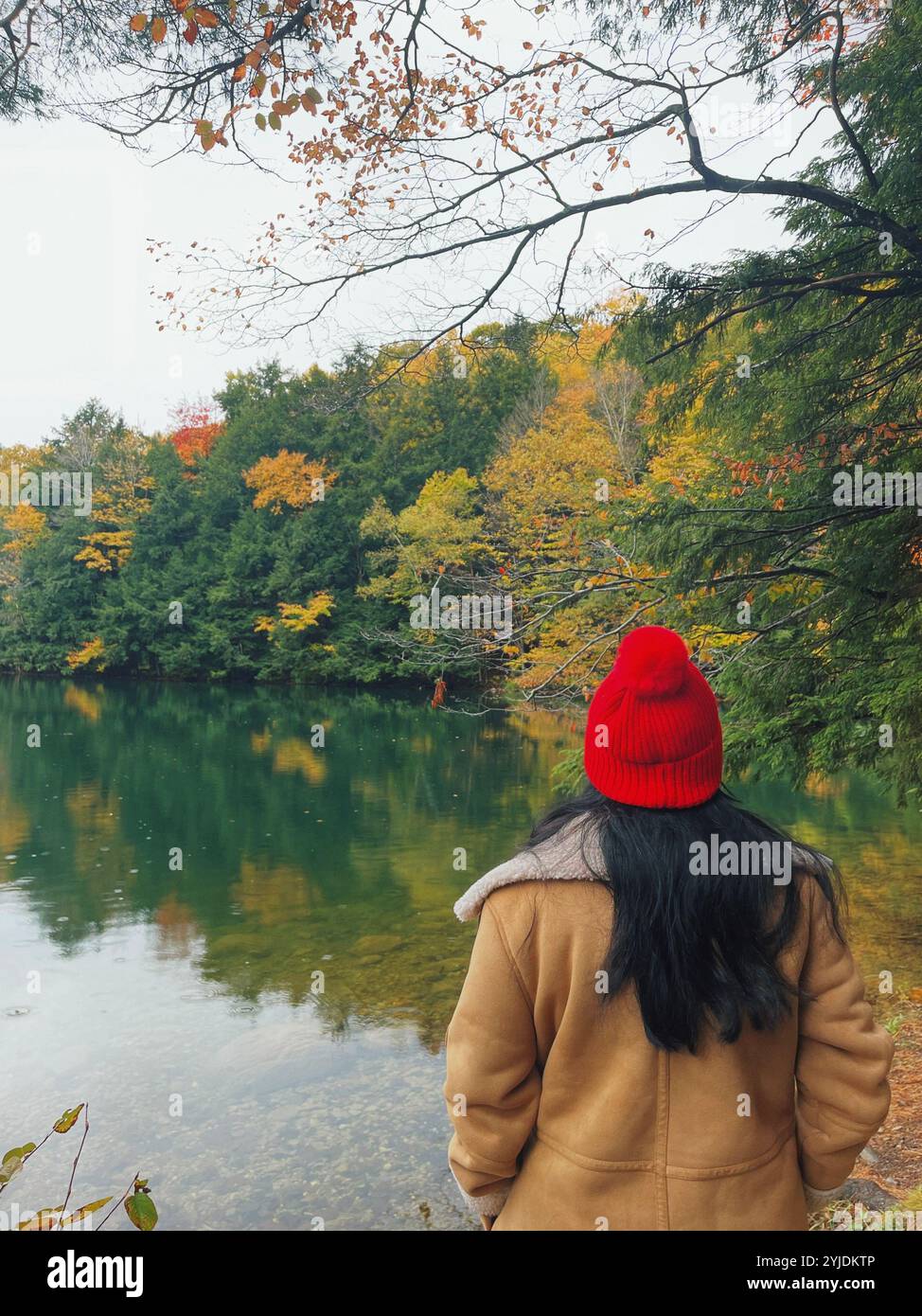 Fille en rouge sur un lac émeraude en automne - Image de stock capturée avec un smartphone