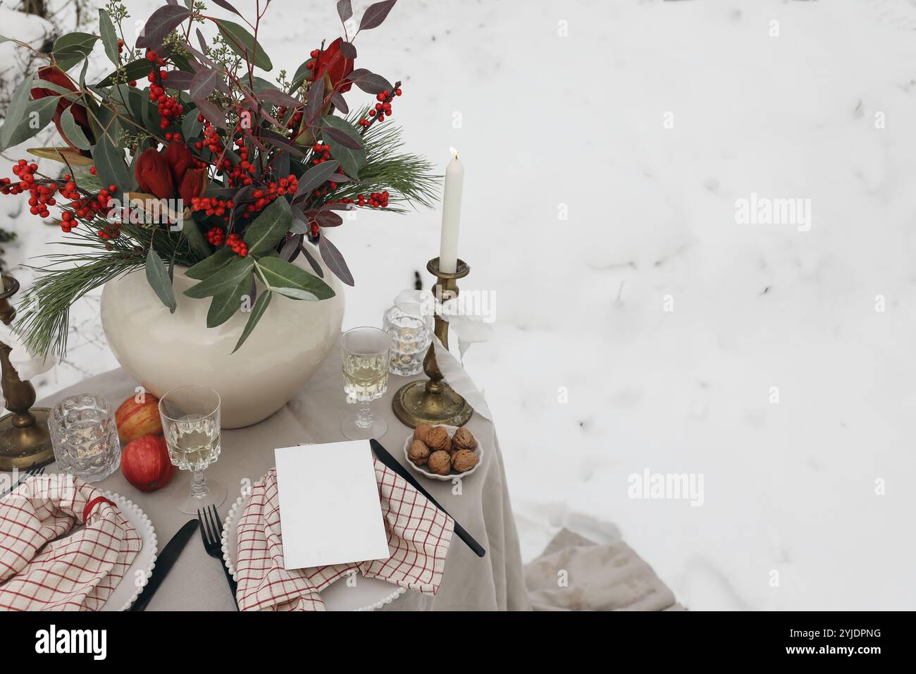 Table extérieure festive de Noël. Dîner du nouvel an. Verre de vin. Houx, amaryllis, pin eucalyptus dans un vase. Mariage d'hiver, Saint-Valentin Banque D'Images