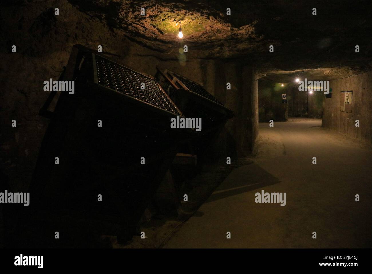 Beaucoup de bouteilles de vin rouge empilées à l'envers à l'intérieur d'une structure carrée en bois vintage dans une ancienne cave en tuf. Banque D'Images