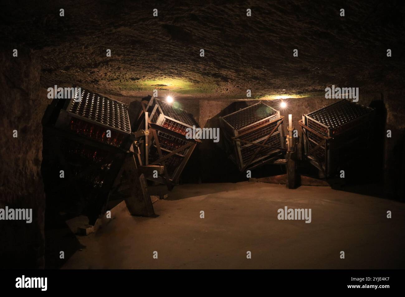 Beaucoup de bouteilles de vin rouge empilées à l'envers à l'intérieur d'une structure carrée en bois vintage dans une ancienne cave en tuf. Banque D'Images