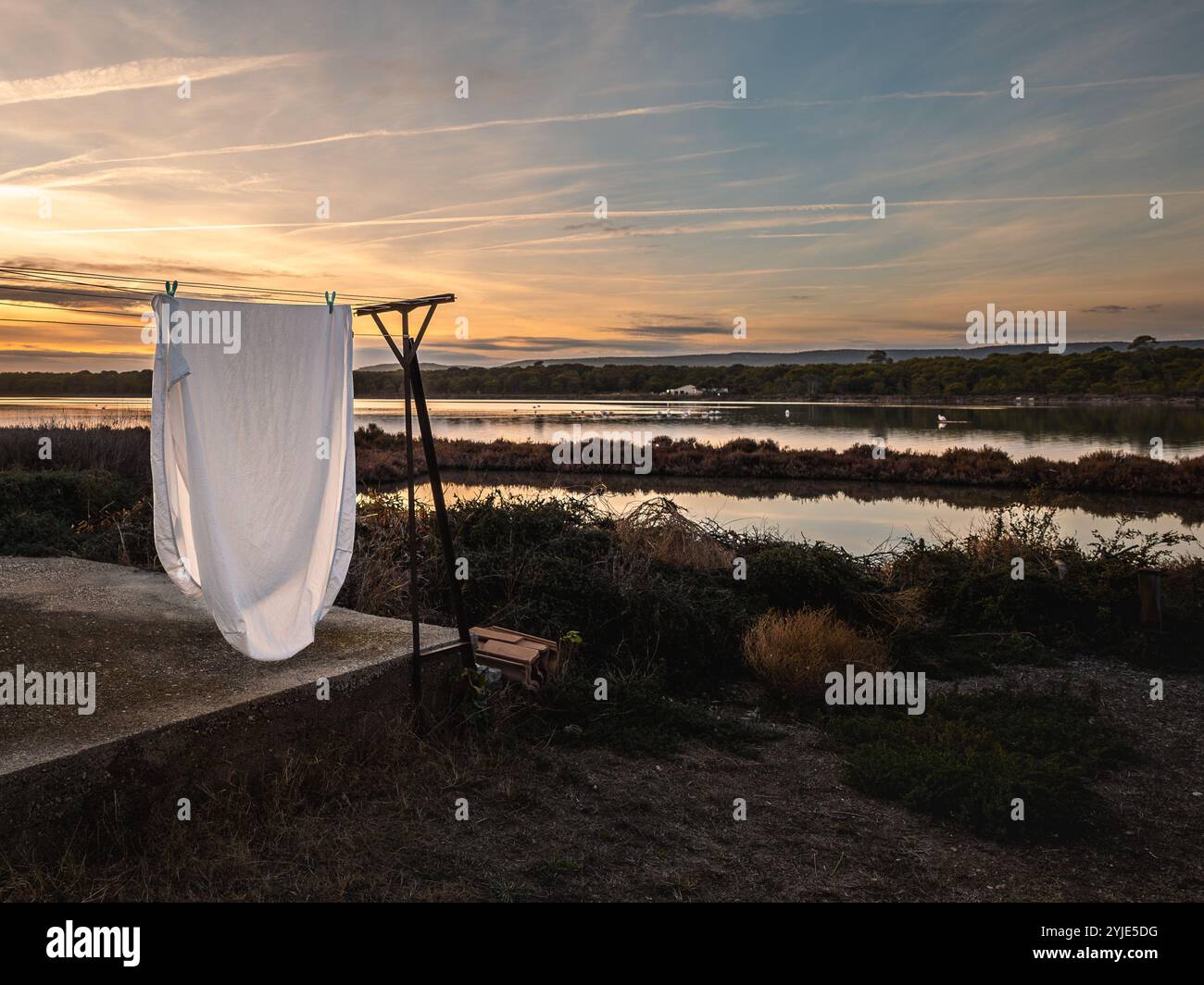 Corde à linge avec draps blancs au coucher du soleil sur les champs Banque D'Images