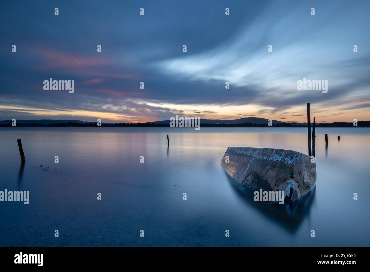 Lac tranquille au crépuscule avec reflets et jetée Banque D'Images